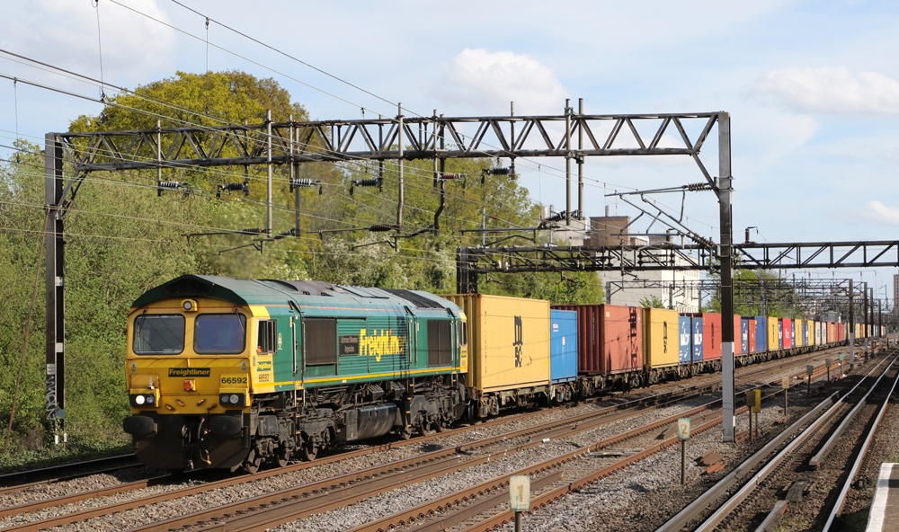 Green and yellow box-cab diesel pulling freight train