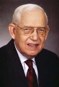 White-haired man in coat and tie