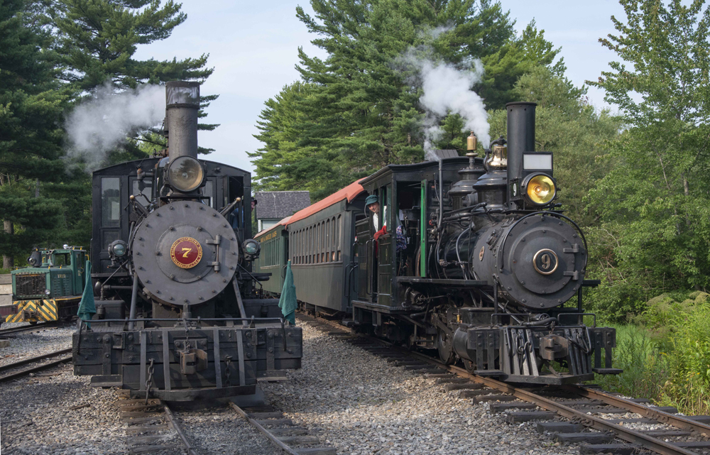 Two small locomotives under steam with trains