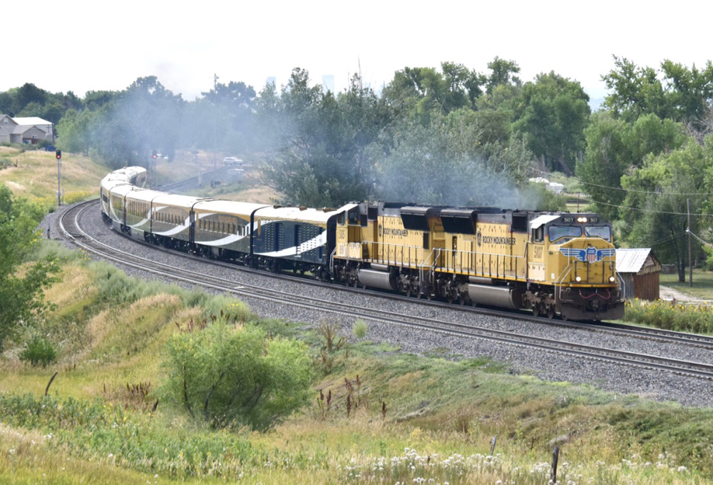 Passenger train with yellow locomotives and blue-and-white cars on curve