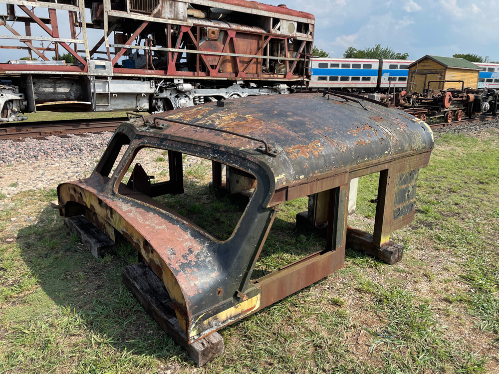 Section of diesel locomotive rook on ground next to engine being rebuilt