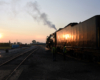 Railroad workers near a steam locomotive in low angle sunlight.