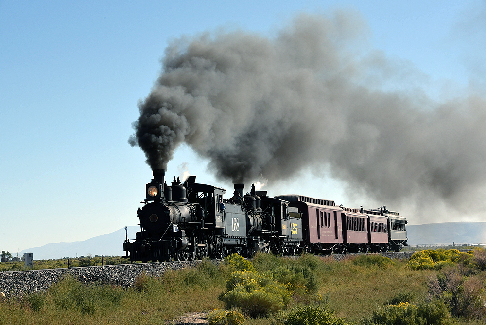 Two old-time steam locomotives double-head on a passenger train.