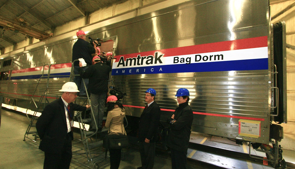 People wearing hard hats entering a stainless steel passenger car