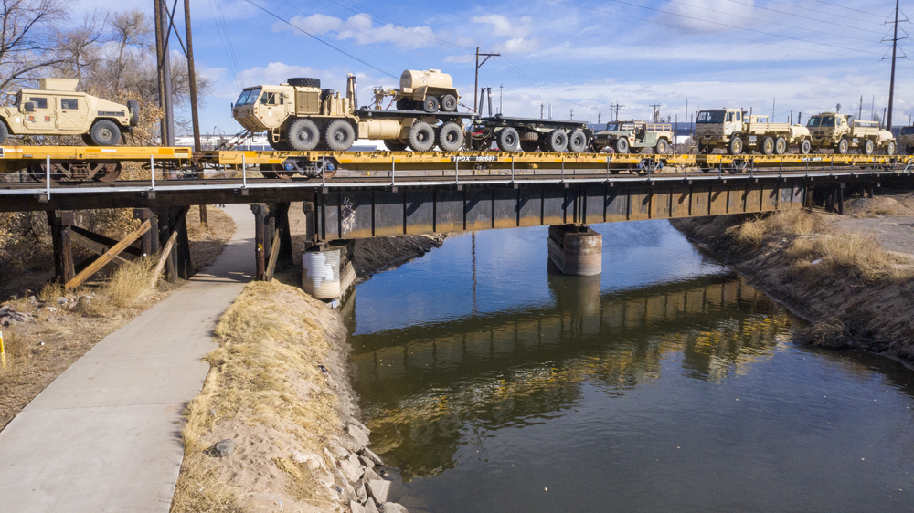 Military equipment on flatcars crossing river