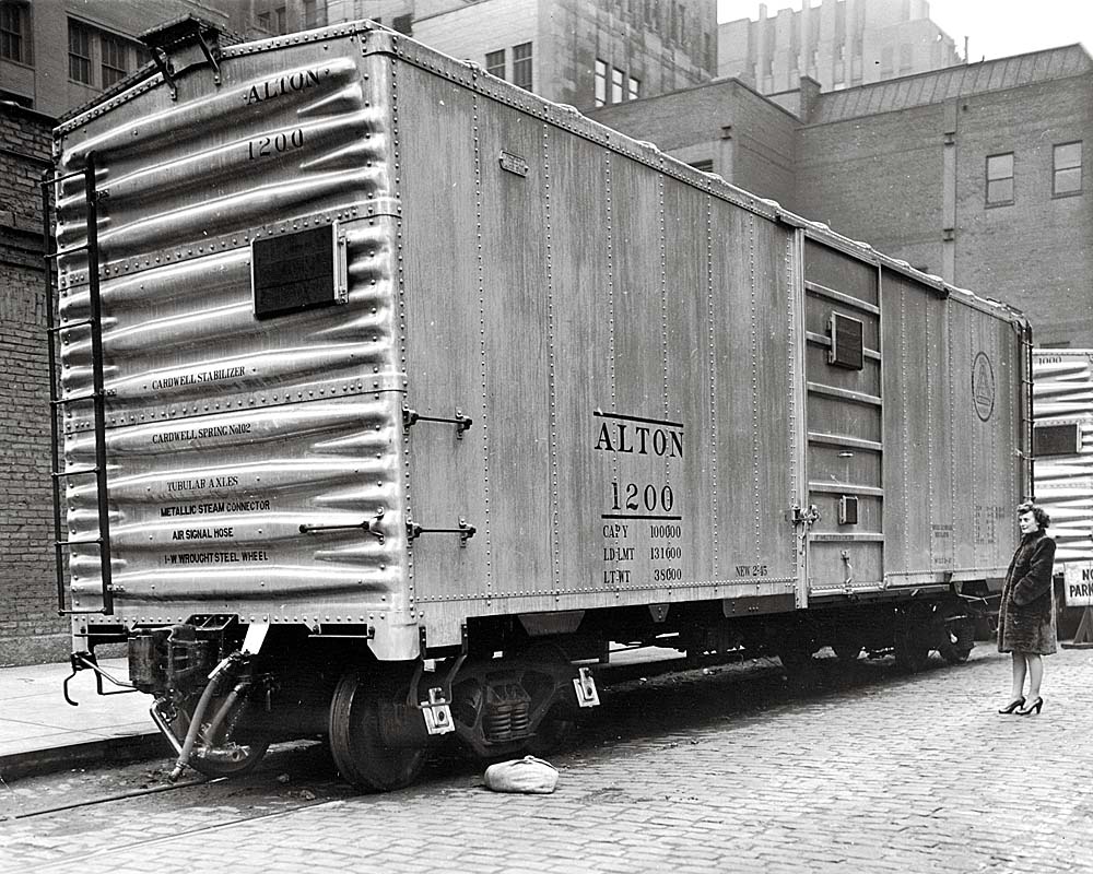 Silver-colored boxcar among tall brick industrial buildings