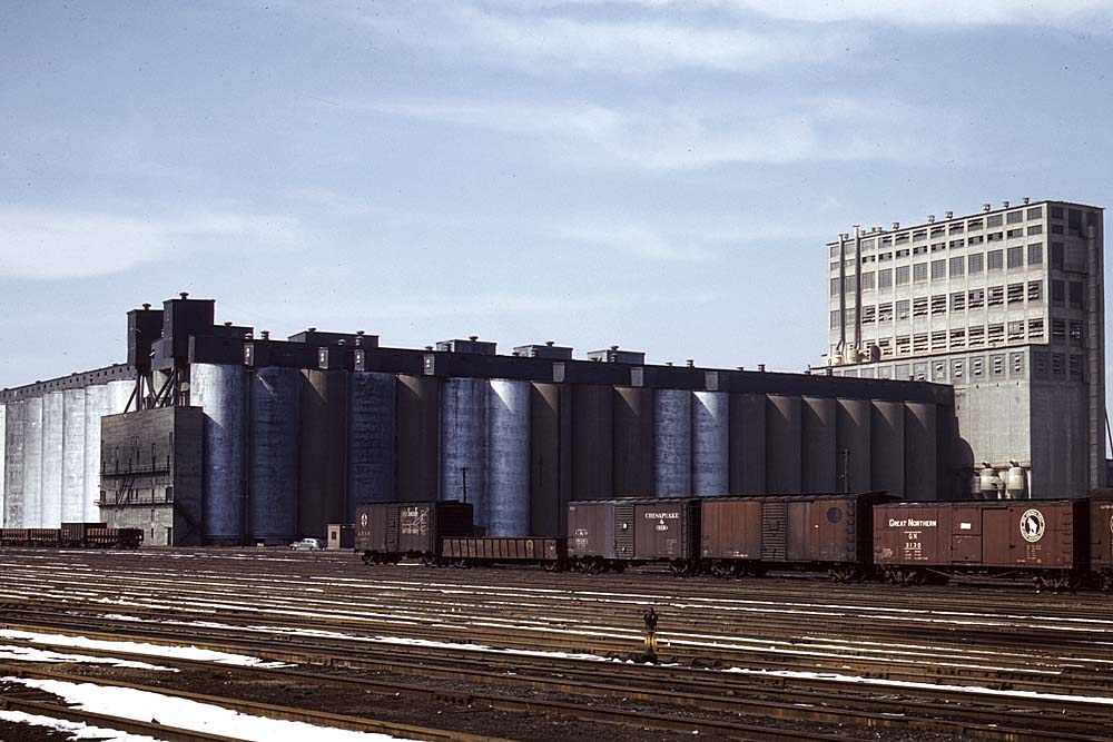 Brown boxcars in front of concrete grain elevator