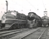 Black-and-white three-quarter-angle photo of three locomotives lined up on adjacent tracks 