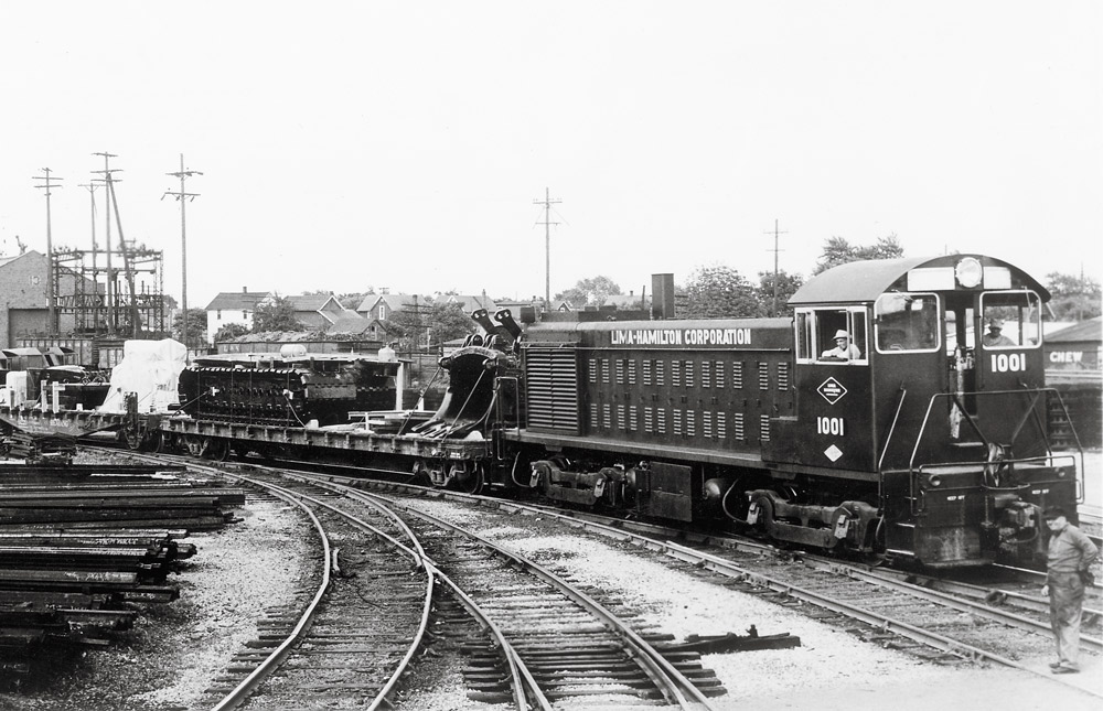 Black-and-white three-quarter-angle photo of diesel switching locomotive with freight cars.
