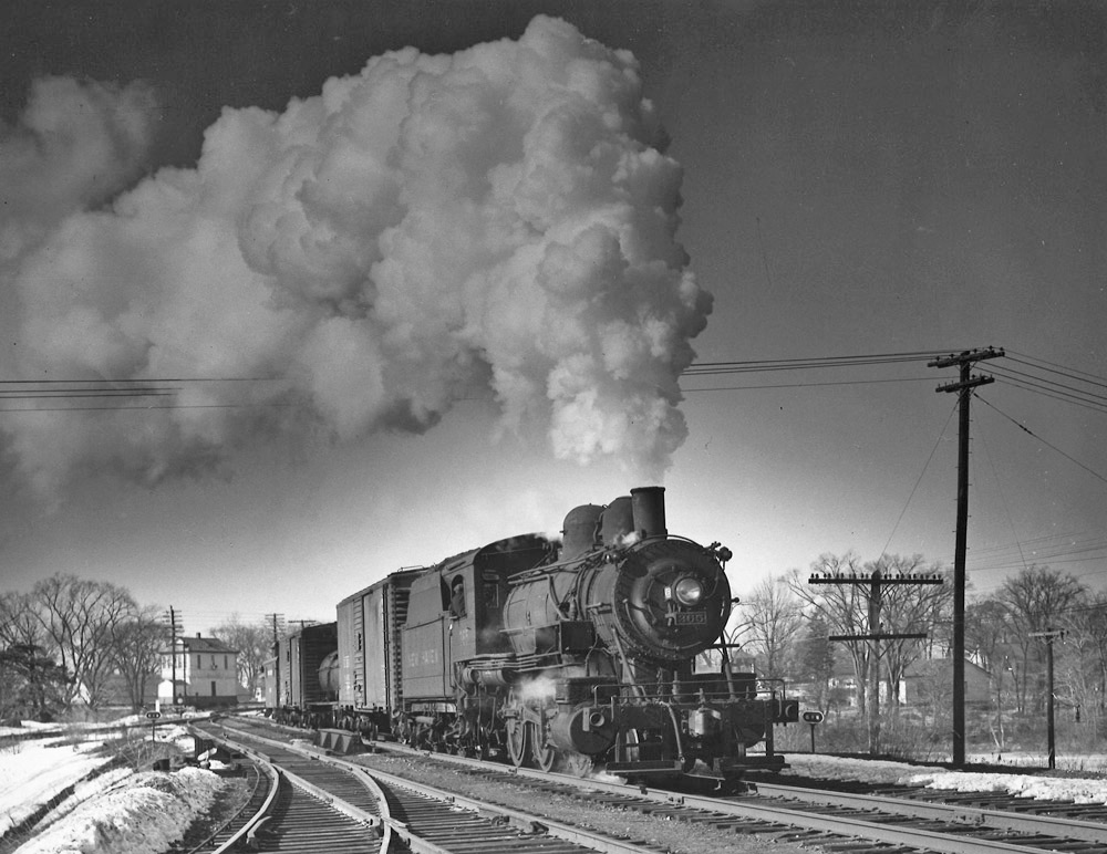 Black-and-white photo of steam locomotive with short freight train.