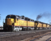 Three-quarter-angle color photo of four Union Pacific road-switcher diesel locomotives on freight train.