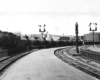 Black-and-white photo of steam locomotive with long train of tank cars