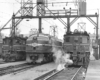 Black-and-white view of front ends of three electric locomotives on adjacent servicing tracks.