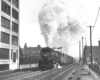 Black-and-white photo of steam locomotive with long train of boxcars