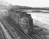 Black-and-white photo of two streamlined diesel locomotives with freight train