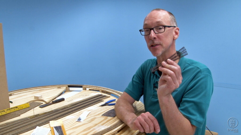 David Popp standing next to the State Line model railroadholding up an N scale turnout