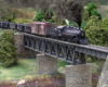 A narrow gauge steam locomotive pulls a train headed by an oversized-looking boxcar