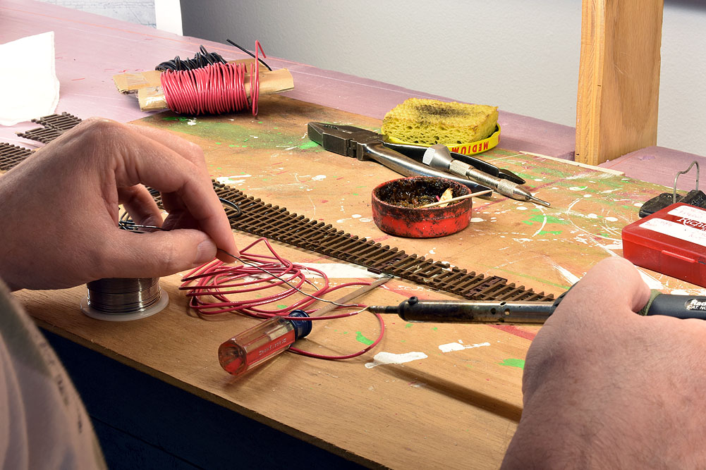 Red stranded wire being tinned with pencil-type soldering iron