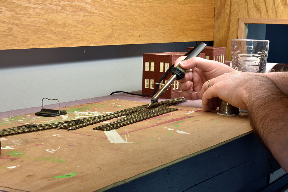 Track on board being soldered with pencil-type soldering iron