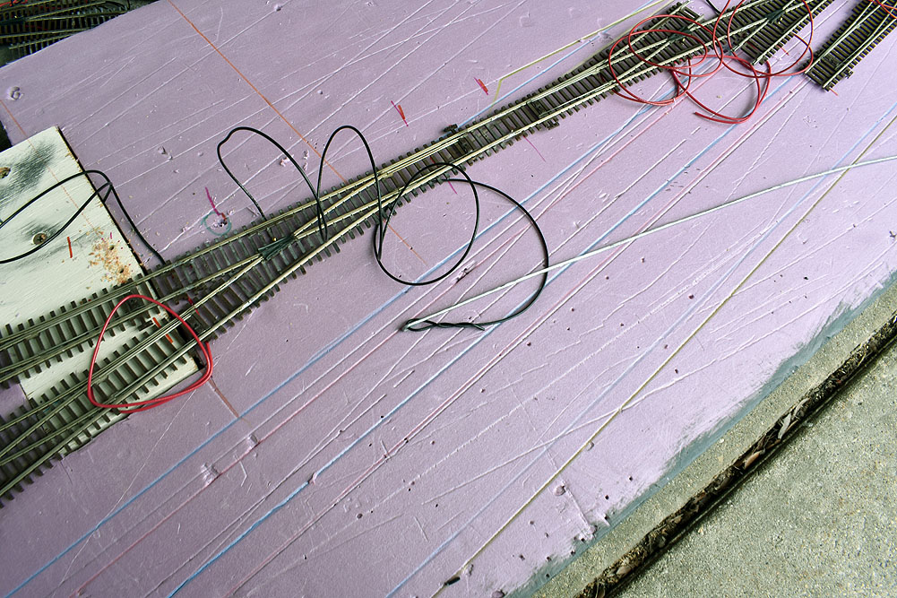 Ladder tracks on pink extruded-foam insulation board with wires attached. Black wire twisted onto baling wire push rod