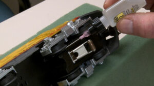 Applying light gear lube to a model locomotive truck with a needle applicator.