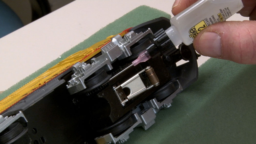 Applying light gear lube to a model locomotive truck with a needle applicator.