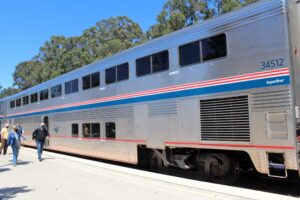 Passengers walk beside bilevel passenger car