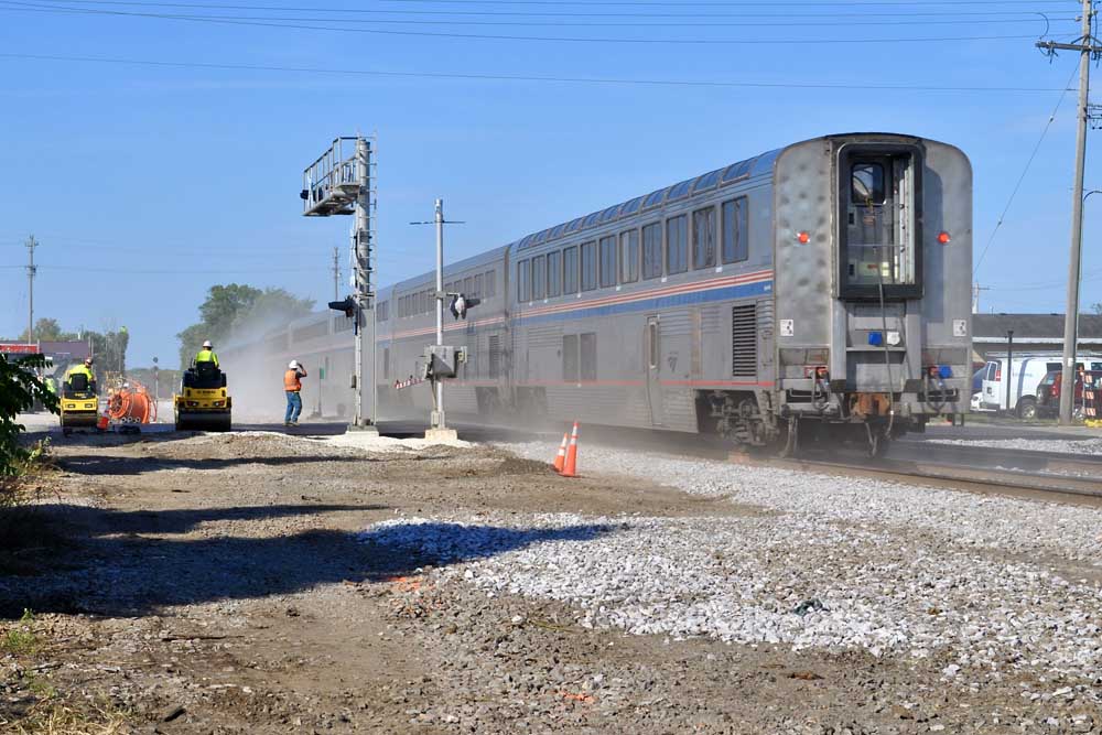 Bilevel passenger train rolls through grade crossing under construction