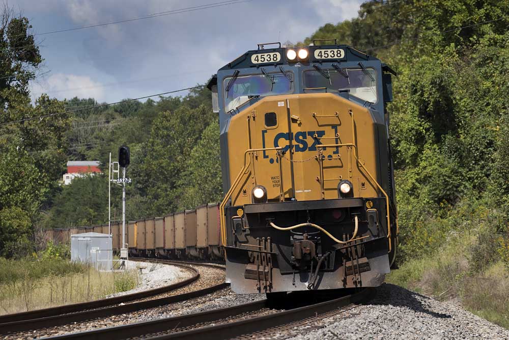 Yellow and blue diesel locomotive with train on curve by signal