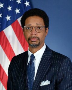 Man in suit in front of U.S. flag