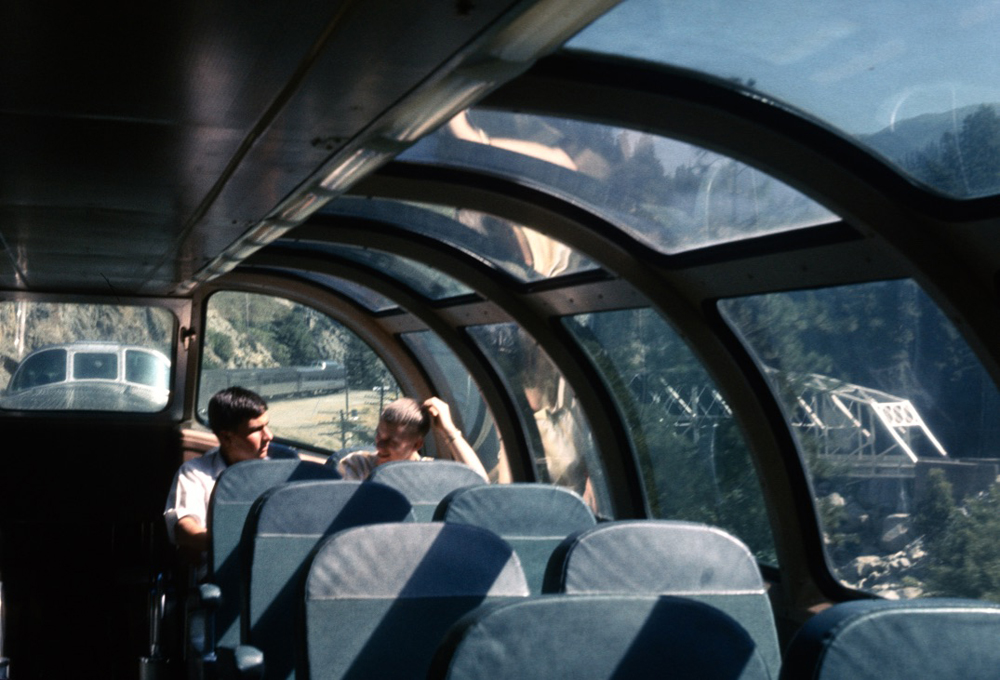Two men sitting in glass dome of passenger car