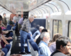 People standing and sitting, facing out windows of passenger car