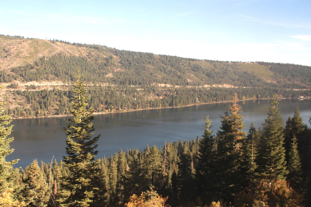 View of mountain lake surrounded by pine trees