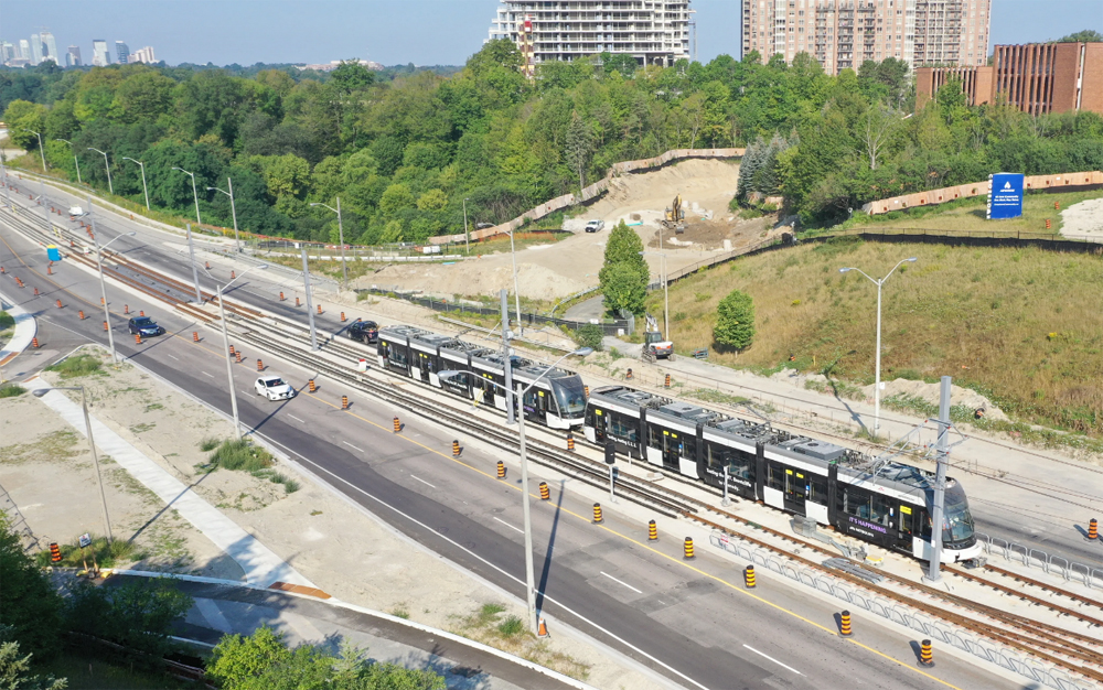 Black and white light rail trainset on tracks in center of roadway