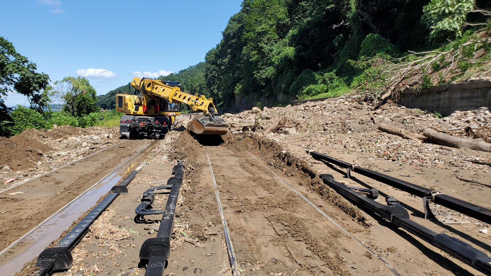 Heavy machinery unearthing mud-covered rail lines