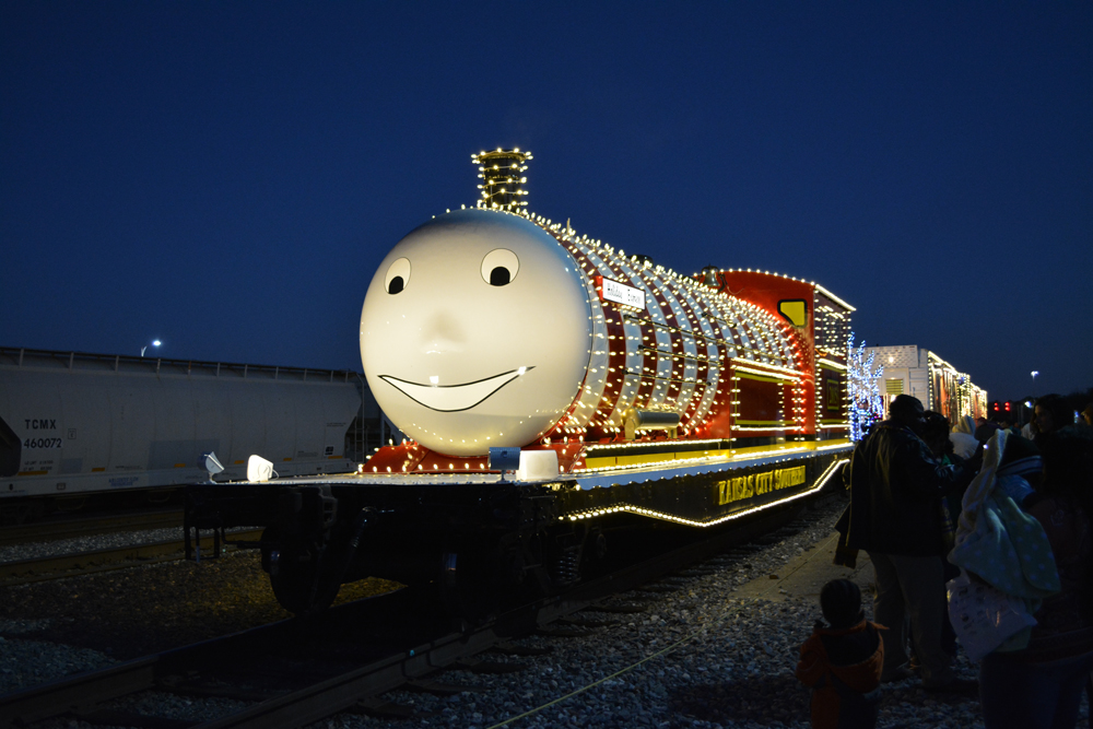 Flatcar decorated to look like steam locomotive, covered with holiday lights