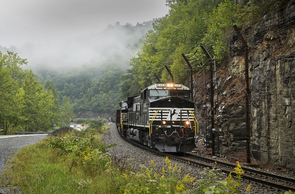 Black locomotives lead train around curve in mountains