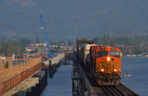 Train crossing bridge next to another bridge under construction