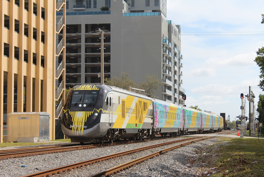 Pasenger train passes tall buildings