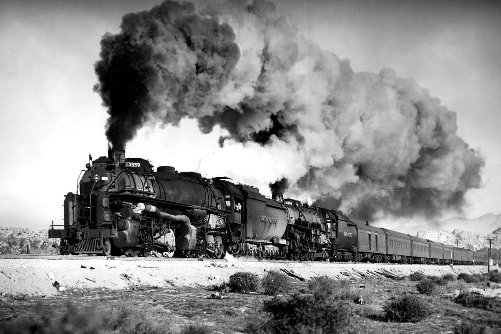 Two steam locomotives power a heavyweight passenger train