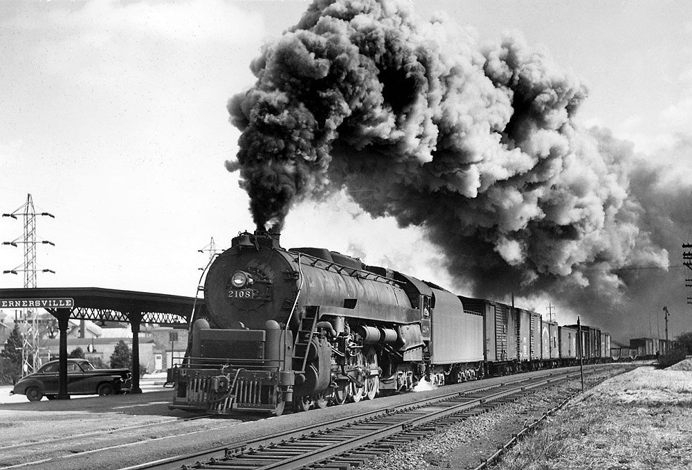 Black-and-white photo of steam locomotive with freight train