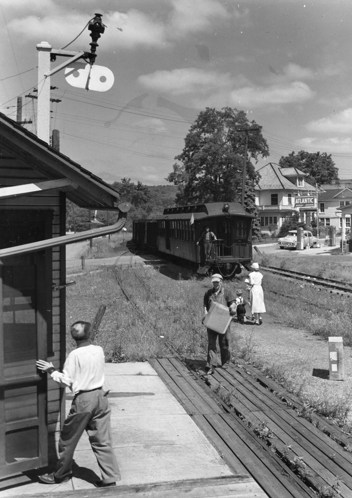 Man at station with train stopped yards away.