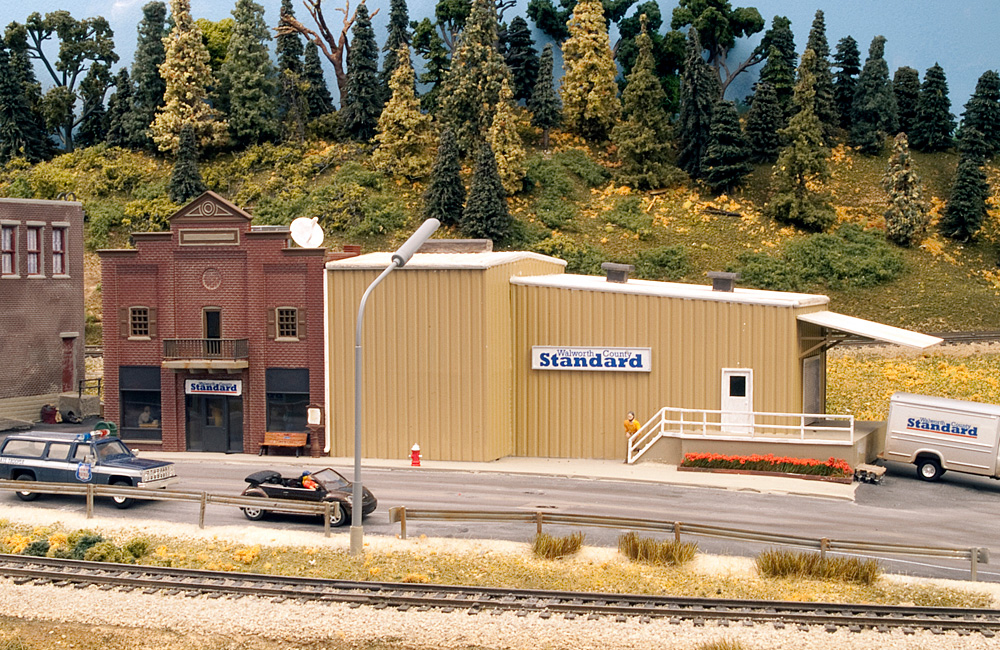 A model of a brick building with corrugated steel annex bears a sign reading “Walworth County Standard”