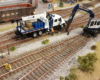 A track crew use a pair of blue-and-white hi-rail vehicles to work on track in a yard