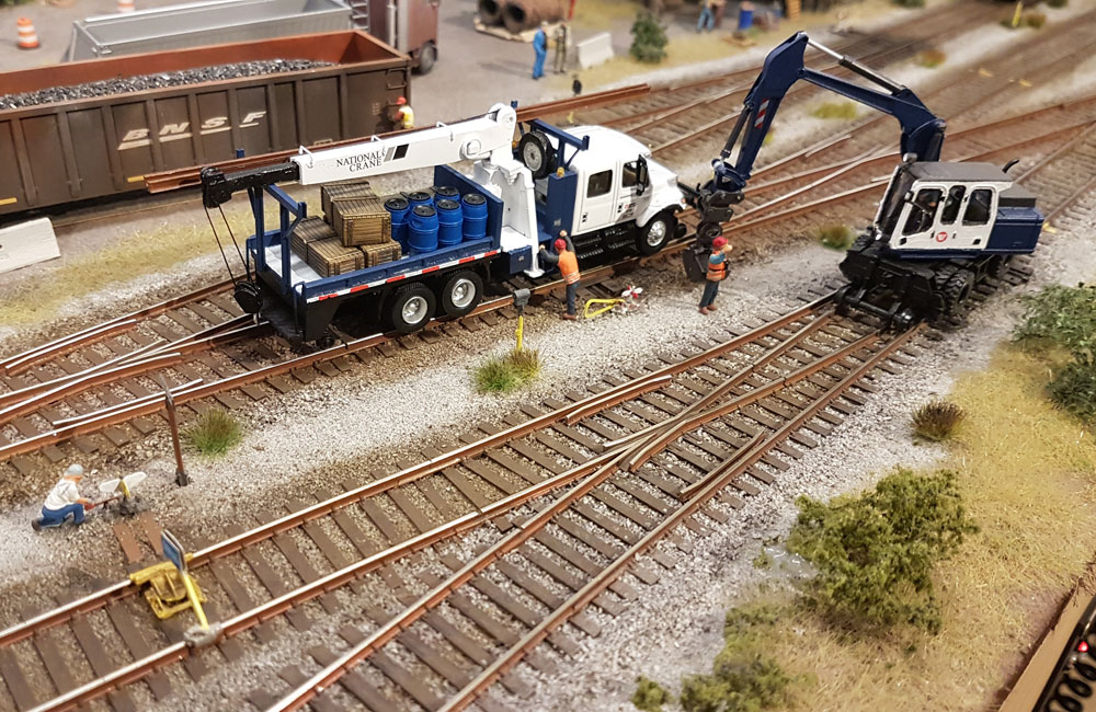 A track crew use a pair of blue-and-white hi-rail vehicles to work on track in a yard