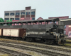 A black, silver, and white diesel pushes white refrigerator cars back alongside an icing platform