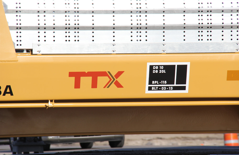 A rectangular, black panel with white lettering is seen on the side of a TTX auto rack car
