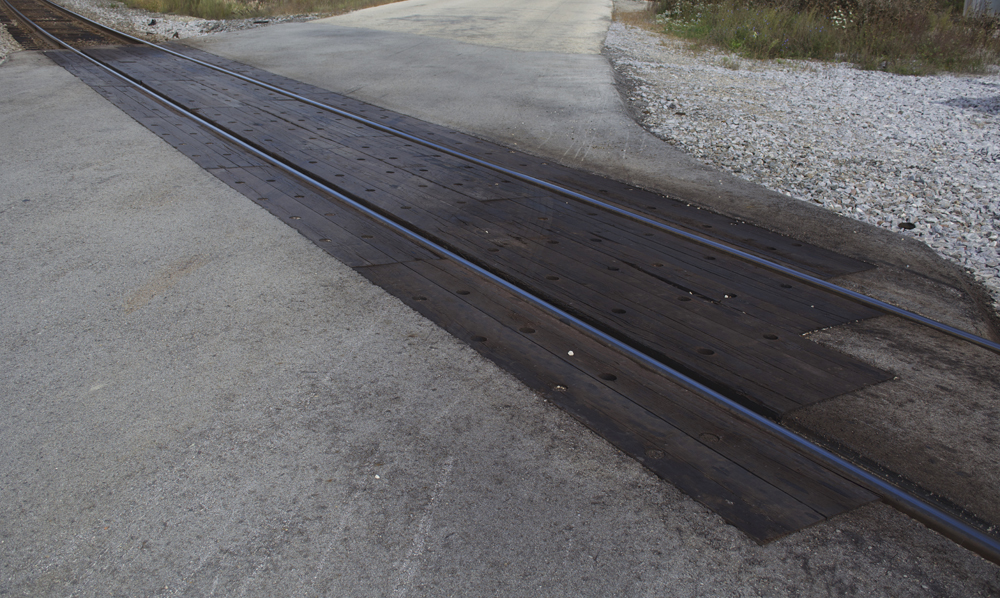 Recently installed wood plank crossing on secondary asphalt road.