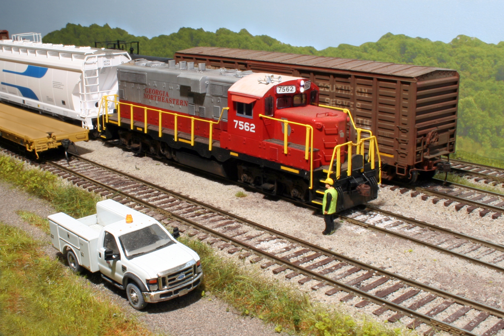 Model locomotive with model person next to it on a layout