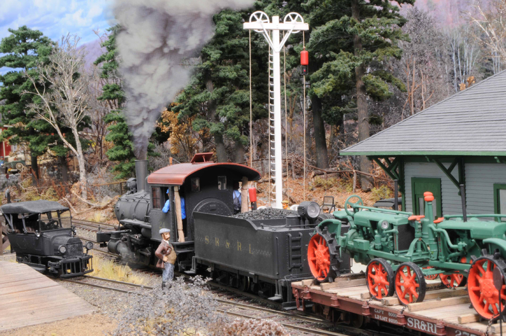 A smoking model steam locomotive on a layout